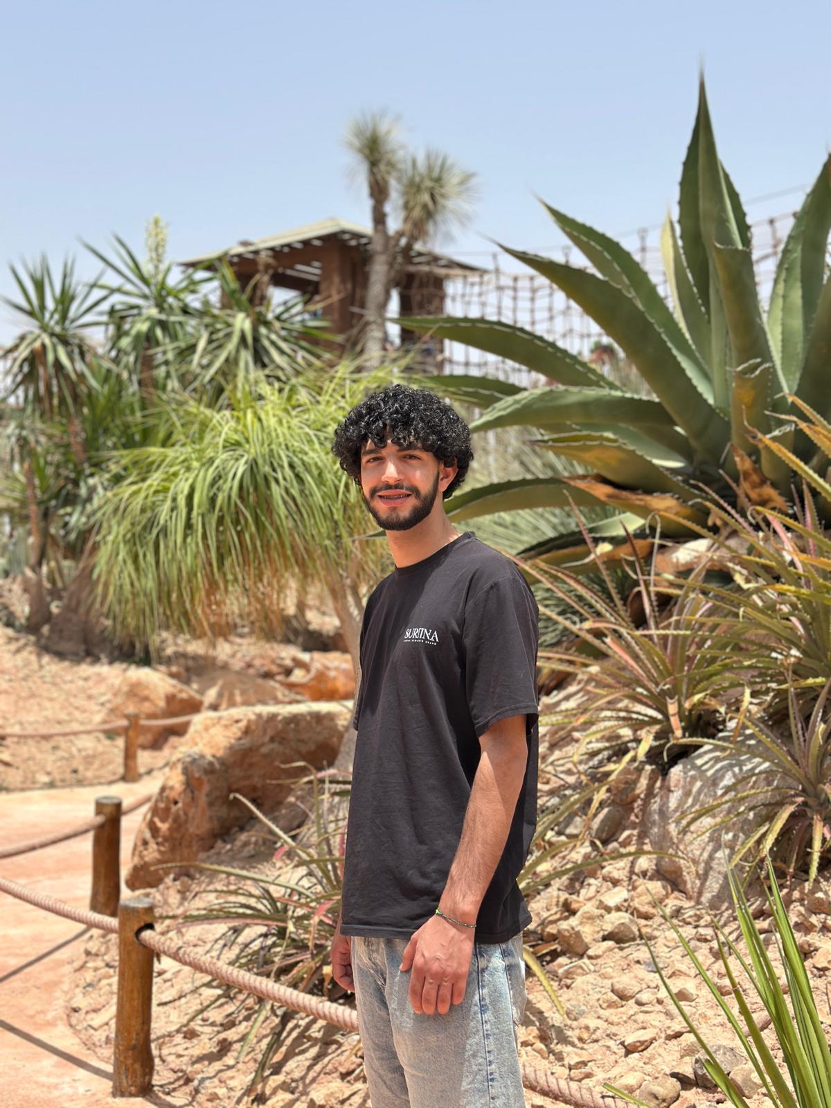 Moha standing among agave and palms in a sunlit desert garden in Morocco